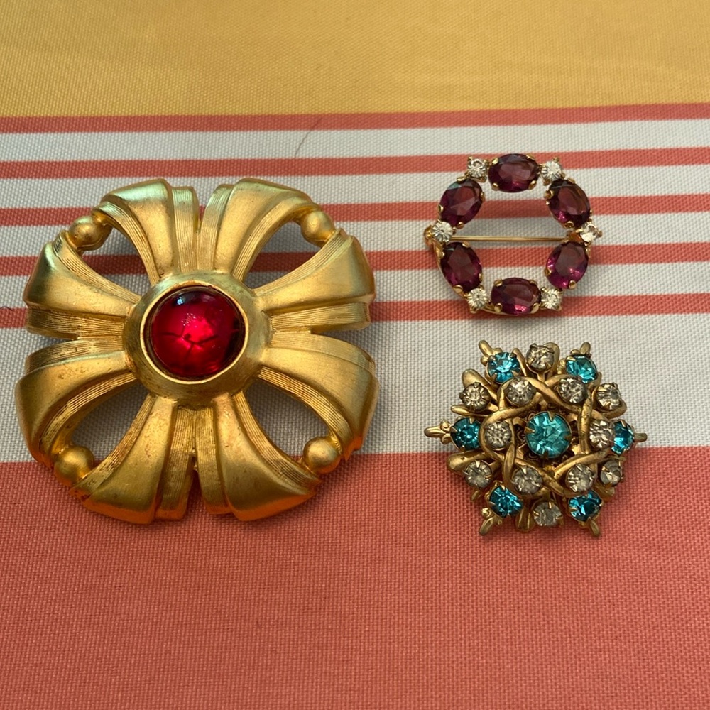 3 unmarked costume pins. Red, blue, purple rhinestones. No missing rhinestones.